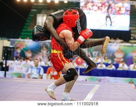 JAKARTA, INDONESIA - NOVEMBER 15, 2015: Savas Bekar of Turkey (red) fights Ndene Top of Senegal (black) in the men's 65kg Sanda event at the 13th World Wushu Championship 2015 in Jakarta.