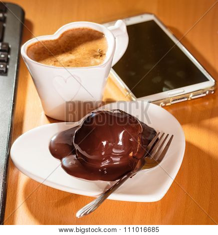Cup Of Coffee And Chocolate Cake Next To Computer.