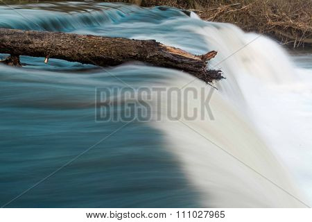 Log on top of waterfall resisting flow of river