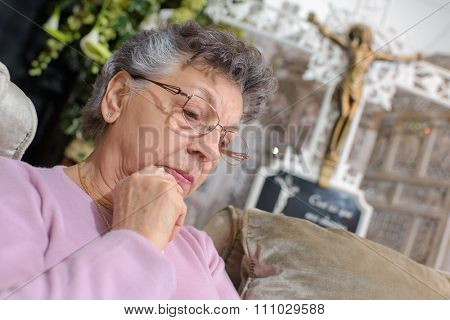 elderly woman in front of crucifix