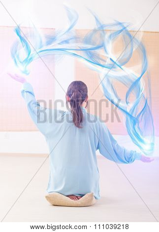 Beautiful woman doing qi gong tai chi exercise or reiki wearing professional, original Chinese clothes at gym