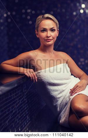 people, beauty, spa, healthy lifestyle and relaxation concept - beautiful young woman sitting in bath towel