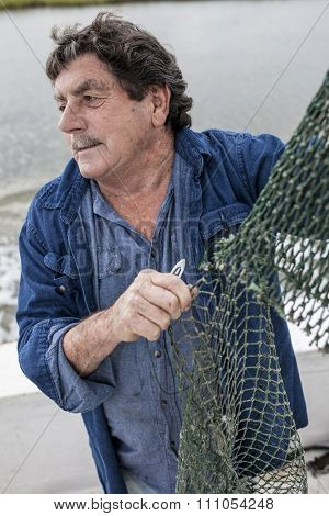 Weathered fisherman mending nets on the deck of a boat