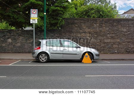 Auto Street fissata con portaruota metallo giallo. Gli alberi crescono dietro muro