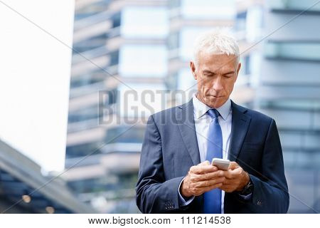 Portrait of confident businessman with his mobile phone outdoors