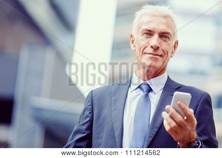 Portrait of confident businessman with his mobile phone outdoors
