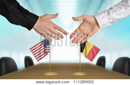 United States and Belgium diplomats shaking hands to agree deal