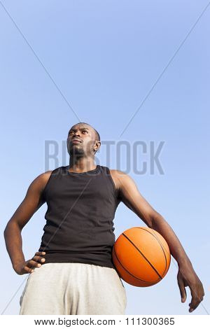 Afroamerican man street basket player holding a basketball against blue sky