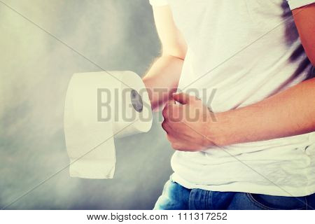 Young man with stomach issues holding toilet paper.