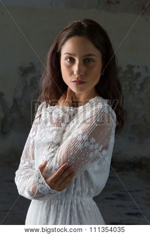 Antique edwardian lace dress worn by a beautiful woman against an old wall
