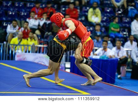 JAKARTA, INDONESIA - NOVEMBER 17, 2015: Kazbek Mamaev of Russia (red) fights Van Cao Hoang of Vietnam (black) in the men's 65kg Sanda event at the 13th World Wushu Championship 2015.