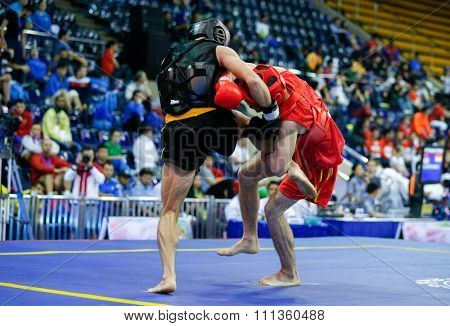 JAKARTA, INDONESIA - NOVEMBER 17, 2015: Kazbek Mamaev of Russia (red) fights Van Cao Hoang of Vietnam (black) in the men's 65kg Sanda event at the 13th World Wushu Championship 2015.