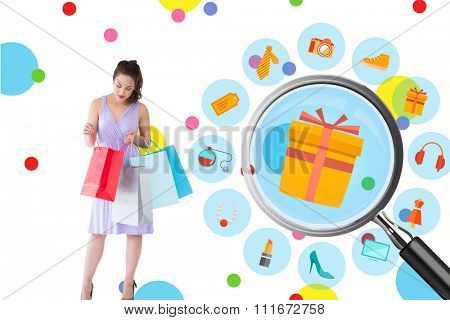 Stylish brunette in purpul dress opening shopping bag against dot pattern