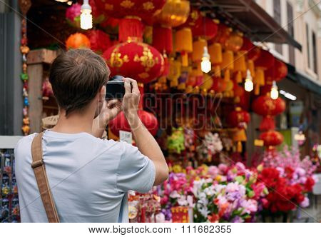 Solo traveler tourist taking photos of red colourful shop store decorations for chines new year in modern asian city