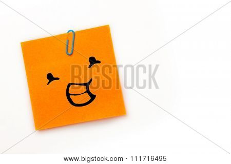 Smiling face against orange adhesive note with a paperclip