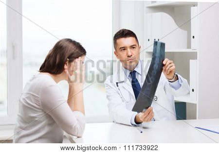 healthcare, surgery, rontgen, people and medicine concept - smiling male doctor in white coat with laptop computer looking at x-ray in medical office