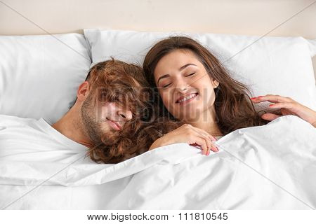 Happy couple snoozing on bed