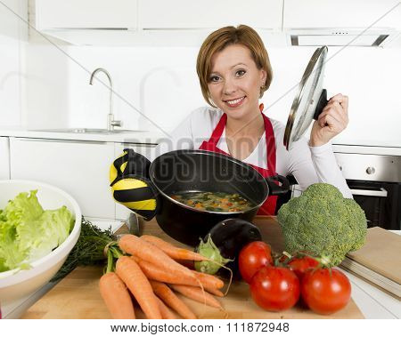 Home Cook Woman In Red Apron At Domestic Kitchen Holding Cooking Pot With Hot Soup Smelling Vegetabl