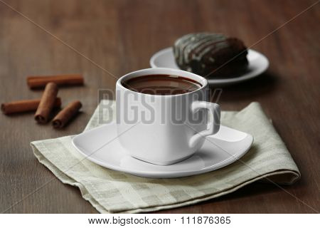 Cup of cacao with biscuits and cinnamon on wooden table