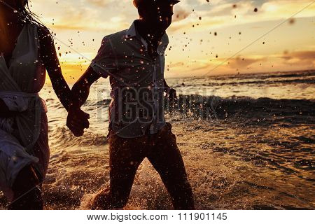 beautiful sunset in the ocean and happy couple running together
