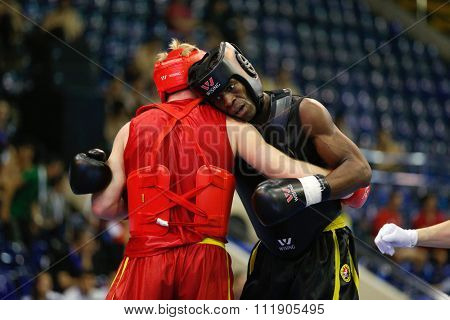 JAKARTA, INDONESIA - NOVEMBER 18, 2015: Dmytro Batok of Ukraine (red) fights Xavier Foupapokam of France (black) in the men's 85kg Sanda event at the 13th World Wushu Championship 2015.