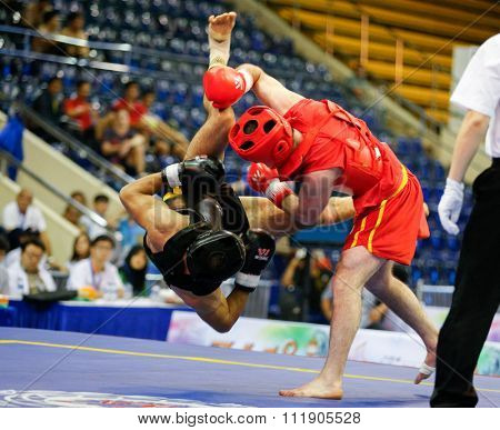 JAKARTA, INDONESIA - NOVEMBER 18, 2015: Ali Abdulkhalikov of Russia (red) fights Ayman Mohamed of Eygpt (black) in the men's 75kg Sanda event at the 13th World Wushu Championship 2015.