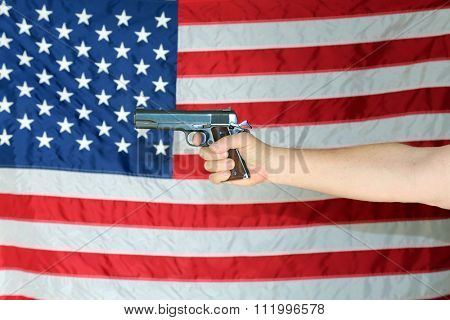 A .45 pistol is held in front of an American Flag. Represents Americas 2nd Amendment, the right to bare arms. Civil Liberty. Personal Protection. Protection of life and property. Gun Control. Guns.