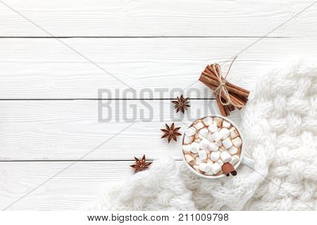 Cup of hot chocolate and white scarf on a white table before christmas eve