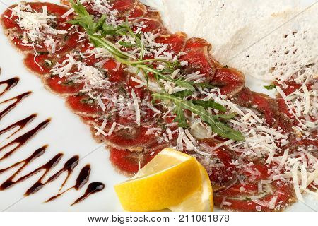 Beef carpaccio with arugula and lemon parmesan and sauce. Close-up