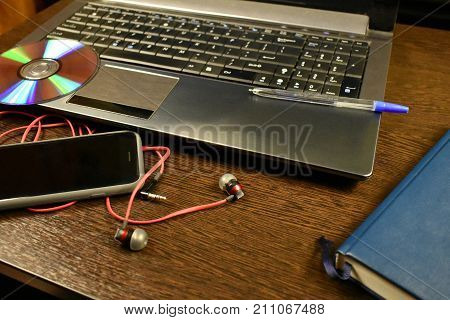 laptop headphones phone pen notebook on the desktop