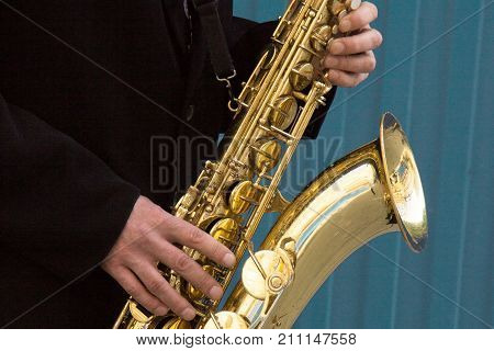 Close Up Of Street Saxophone Player Hands Playing Alto Sax Musical Instrument Over Blue Background ,