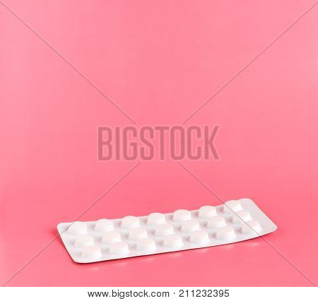 Medicine blister pack of pills on pink background