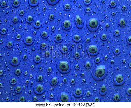 GREEN EYES INSIDE WATER DROPLETS ON BLUE BACKGROUND