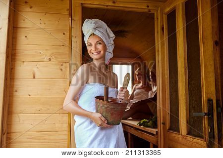 three beautiful young women in towels realxing in wooden sauna. inside shot with natural light.
