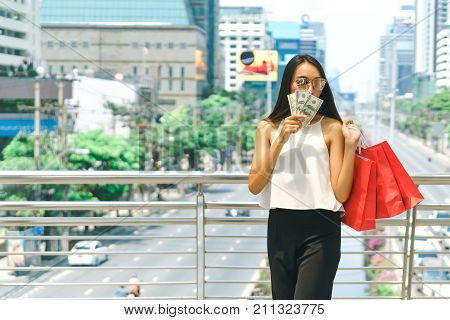 Beautiful young woman walking with many shopping bags shop and holding cash banknotes shopping summer sale and fashion at center complex bangkok.
