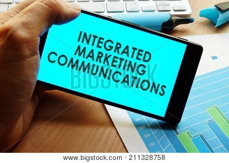 Hand holding smartphone with words integrated marketing communications.