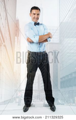 I am successful. Nice handsome successful entrepreneur standing hand crosses and smiling while feeling confident about himself