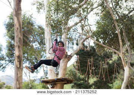 Woman enjoying zip line adventure in park on a sunny day