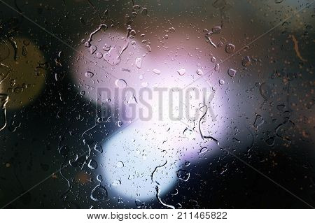 Raindrops On A Car Window With Beautifully Blurred Background Of Street Traffic Lights