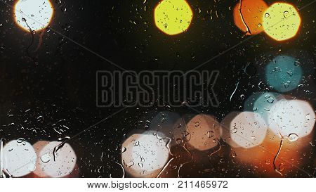 Raindrops On A Car Window With Beautifully Blurred Background Of Street Traffic Lights