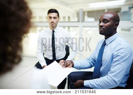 Human resourses manager showing contract to one of candidates for new vacancy