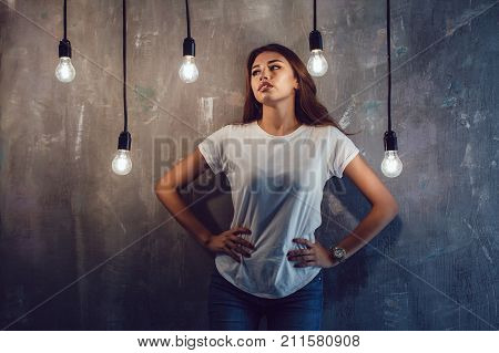 Sexy woman in a white T-shirt on a gray background with light bulbs. Mock-up.