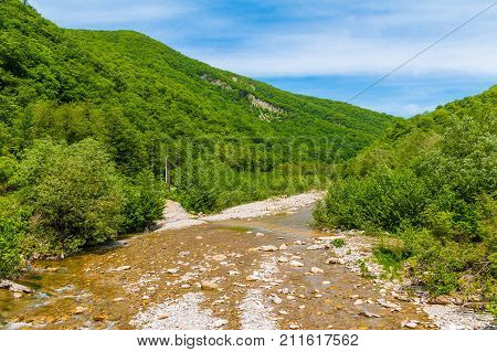 Landscape with Makopse river flowing in ravine on the background of Tamyurdepe mountain in sunny summer day Sochi Russia