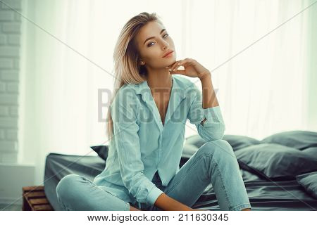 Relaxing woman sitting comfortable in sofa lounge chair smiling happy looking at camera. Resting beautiful young multicultural asian caucasian girl in her 20s .