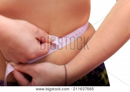 Measurement of woman waist on white background. Measuring the waist with centimeter tape.