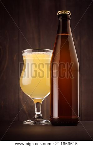 Brown beer bottle NRW and glass tulip with muddy weizen on dark wood board vertical mock up. Template for advertising design branding identity.