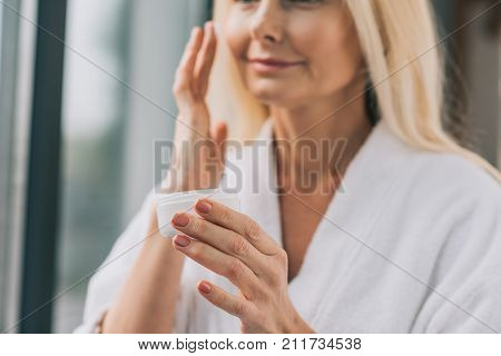Mature Woman Applying Cosmetic Cream