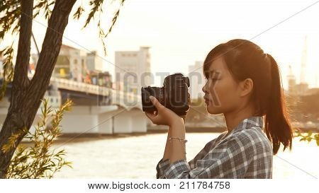 Vietnamese girl photographer takes pictures of nature in the city center at sunset.