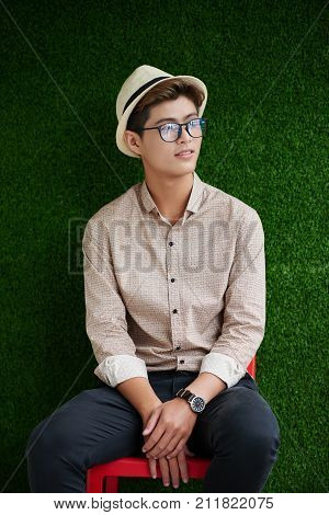 Portrait of handsome stylish Vietnamese young man in hat and glasses