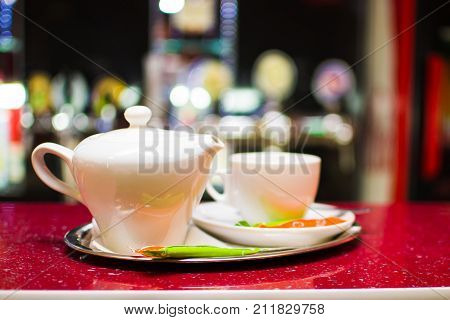 Black tea in a ceramic teapot on a tray with a cup.